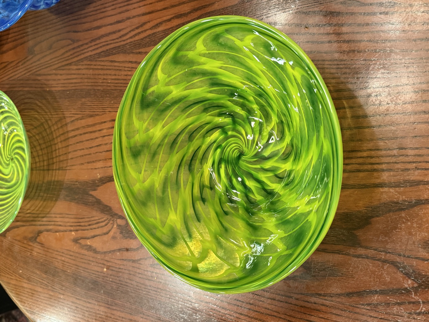 A hand-blown glass platter with green and gold swirls, spun while molten